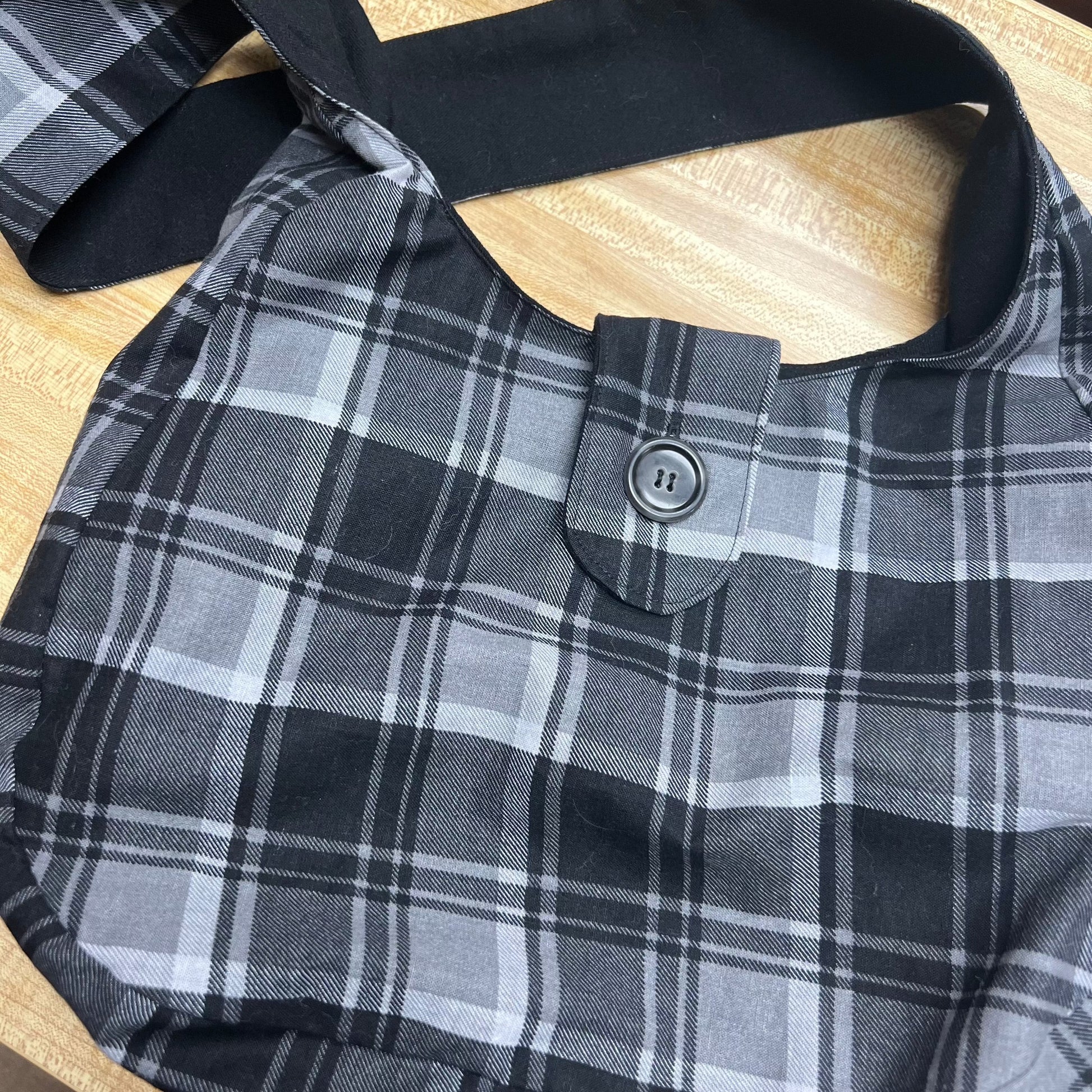 Black & white plaid fabric outer with a black with pockets lining the purse.